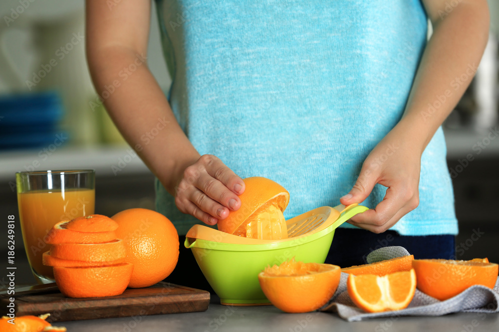Woman making orange juice in kitchen Woman making orange juice in kitchen