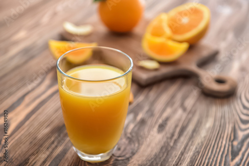 Glass with delicious orange juice on table