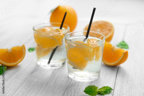 Glasses of delicious cocktails with orange on table