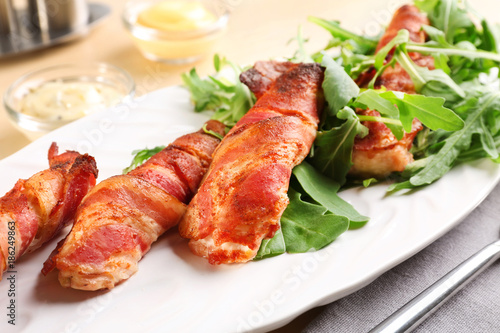 Plate with bacon wrapped chicken nuggets on table, closeup