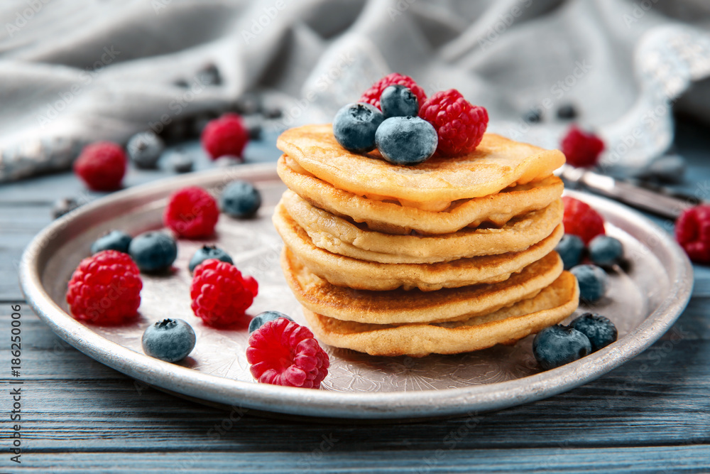 Metal dish with buckwheat pancakes and berries on table Metal dish with buckwheat pancakes and berries on table