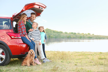 Young family with cute children and dog near car