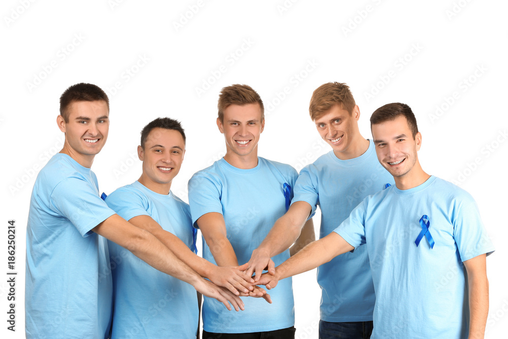 Young men in blue t-shirts putting hands together on white background. Prostate cancer awareness concept Young men in blue t-shirts putting hands together on white background. Prostate cancer awareness concept