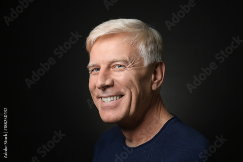 Portrait of smiling mature man on dark background