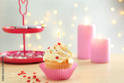 Birthday cupcake with candle on table against blurred background