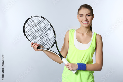 Young woman with tennis racket on light background © Africa Studio