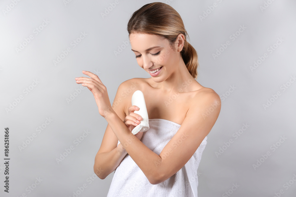 Young woman applying body cream on light background Young woman applying body cream on light background
