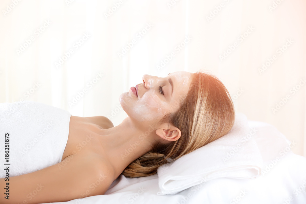 Beautiful young woman with cream on her face in spa salon Beautiful young woman with cream on her face in spa salon