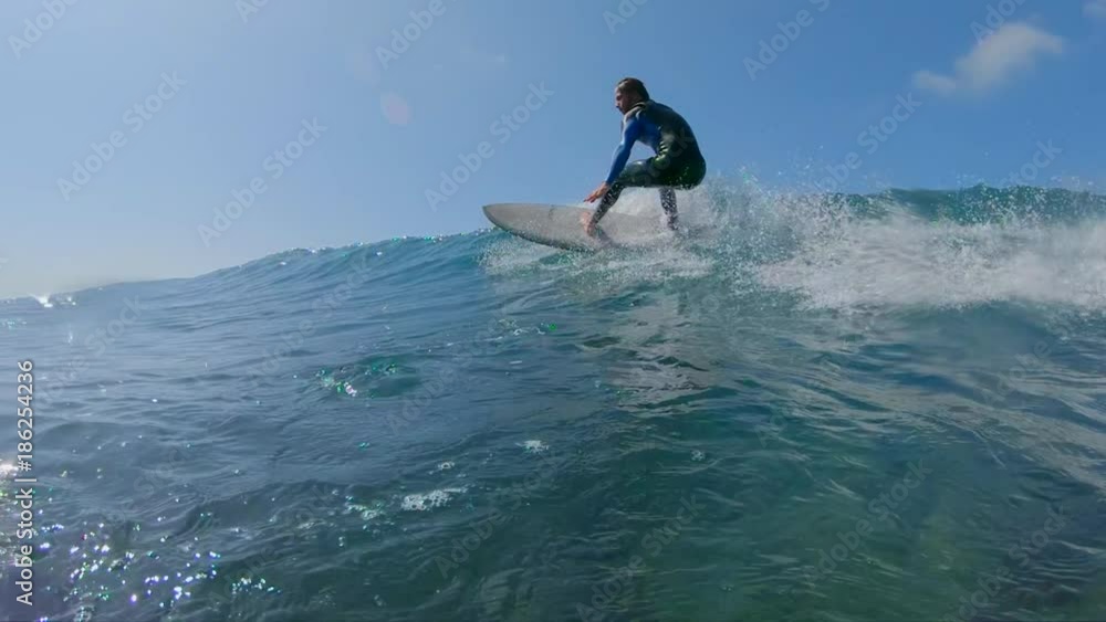 SLOW MOTION, LOW ANGLE, UNDERWATER: Surfer makes a turn on big blue ocean wave on hot sunny day in summer. Surfer carving awesome wave on his cool surfboard. Epic shot of male riding wave on surfboard SLOW MOTION, LOW ANGLE, UNDERWATER: Surfer makes a turn on big blue ocean wave on hot sunny day in summer. Surfer carving awesome wave on his cool surfboard. Epic shot of male riding wave on surfboard