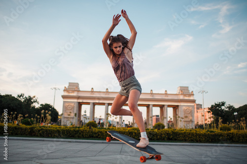 Young sporty woman riding on the longboard in the park