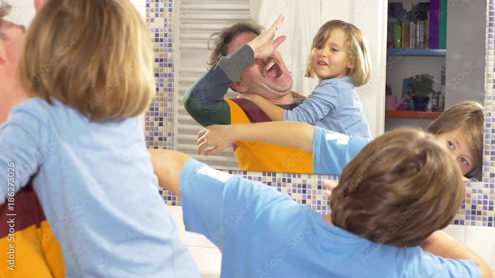 Man dancing with little daughter and son in bathroom in front of mirror Man dancing with little daughter and son in bathroom in front of mirror