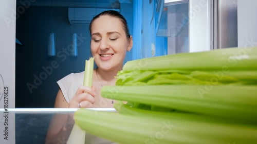 4k footage of happy smiling woman biting fresh celery. OCncept of healthy nutrition photo