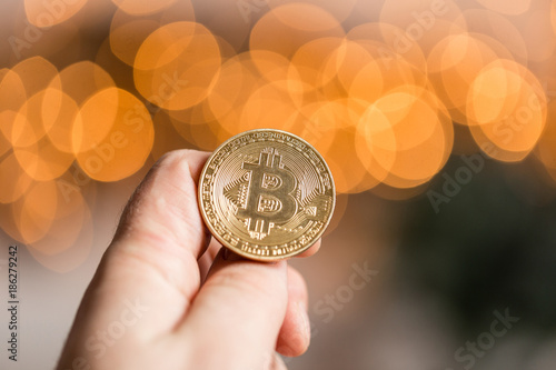Man holding golden bitcoin. On the background blurred bokeh lights. the concept of cryptocurrency
