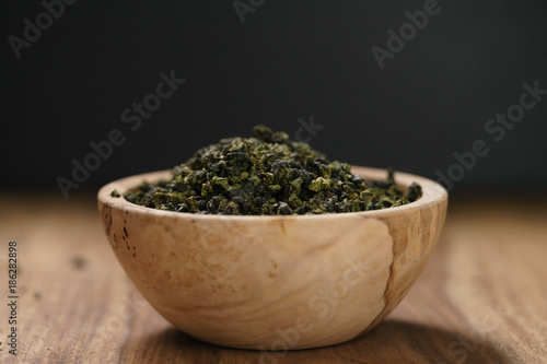 dry organic green oolong tea in wood bowl