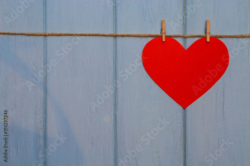 Paper Heart of love with wooden clips on rope on blue wooden background. Romantic symbol. Love concept