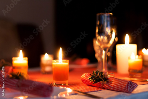 Festive composition with candles and plates. Table decoration. A beautiful table setting, red table cloth, tablecloth in the box. Christmas dinner. A Napkin decorated with inscription Merry Christmas.