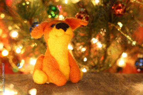 Symbol of new years 2018 yellow dog. Bolt. New years greetings background. Fancy handmade toy from wool on bokeh Christmas background. Copyspace for congratulations.