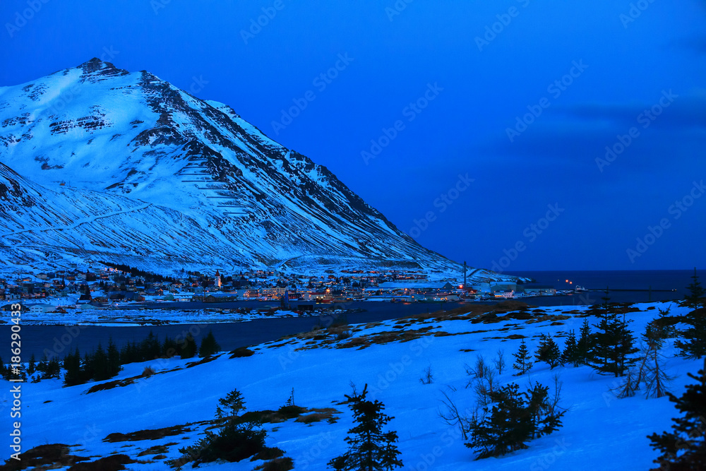 Fototapeta premium Beautiful view on Siglufjordur at dusk in winter. Siglufjordur is a small fishing town in a narrow fjord on the northern coast of Iceland.