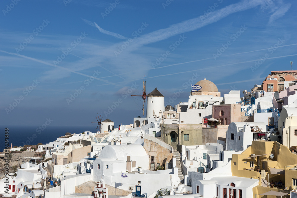 Old Town of Oia on the island Santorini, white houses, windmills and churchs with blue domes