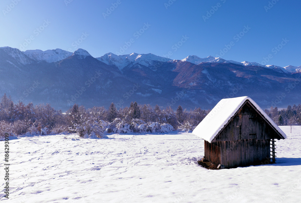 small barn on a sunny winter day with mountains