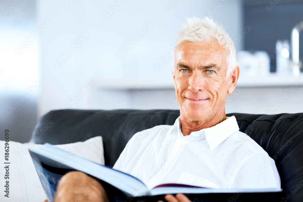Handsome sennior man reading a book relaxing on a sofa Handsome sennior man reading a book relaxing on a sofa