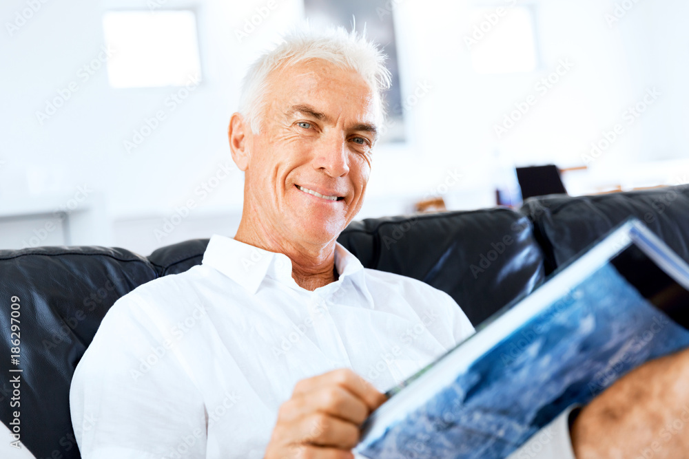 Handsome sennior man reading a book relaxing on a sofa Handsome sennior man reading a book relaxing on a sofa