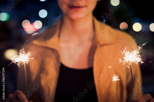 lady hold two firesparklers blink in her hand at night toning, with smile face photo