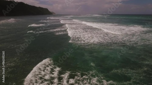 Aerial drone footage of ocean waves breaking before the shore on sunset. Bali, Indonesia