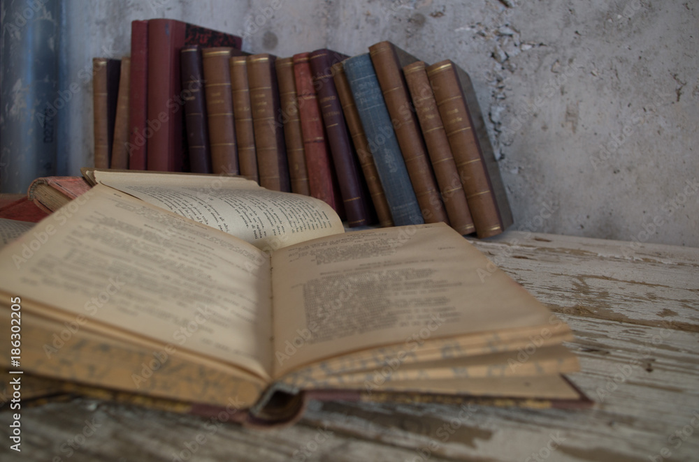 Naklejka premium libri antichi chiusi e aperti su tavolo legno e contro muro grezzo