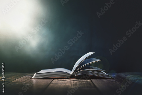 Open Bible with a light coming from above on a wooden desk