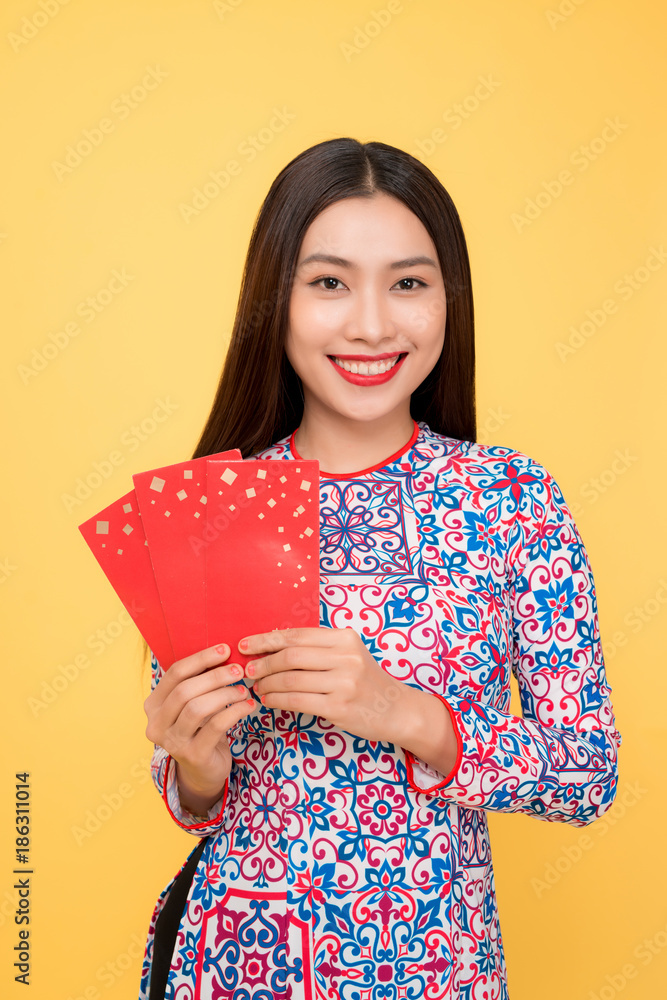 Pretty smiling Vietnamese woman with red envelopes isolated over yellow background Pretty smiling Vietnamese woman with red envelopes isolated over yellow background