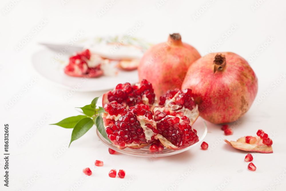 The broken pomegranate fruit with leaves on white The broken pomegranate fruit with leaves on white