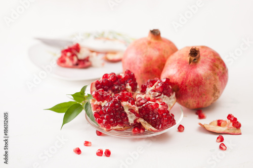 The broken pomegranate fruit with leaves on white