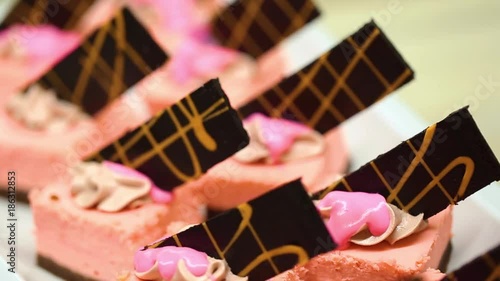 Closeup view of many small pink cakes served on table for cocktail party or on shelves at store. photo