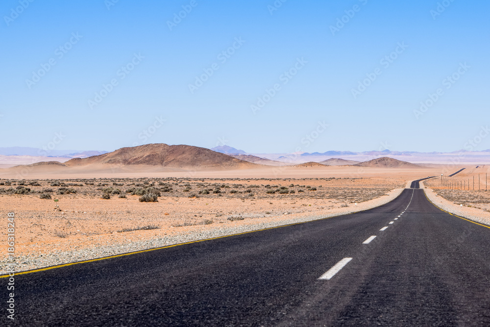 Beautiful wide angle view of the B4 road between Lüderitz and Keetmanshoop near Garub in Namibia, Africa. The road cuts through the famous Namib Desert. Mountains in the background.