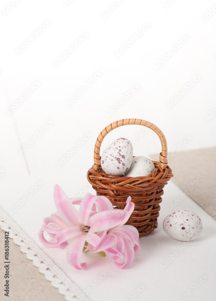 Little Braided Wooden Basket With Chocolate Eggs On Handmade Natural Linen Napkin. Hyacinth Flowers Little Braided Wooden Basket With Chocolate Eggs On Handmade Natural Linen Napkin. Hyacinth Flowers