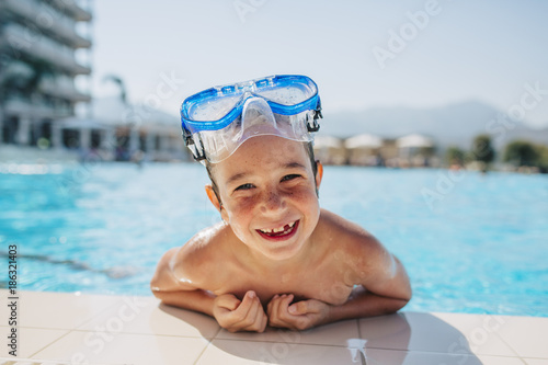 A happy young boy leaning on the edge of a pool photo