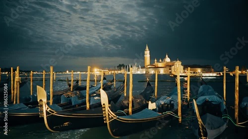 tilt up view of moonlit gondolas tied up at piazza san marco, venice