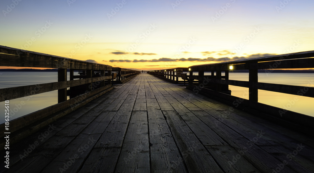 Morning on an ocean pier with wood planks and orange sky Sidney British Columbia Canada