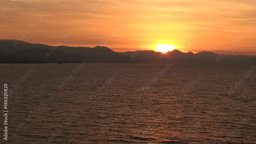Sun sets behind Corfu Island mountains, wide Sun sets behind Corfu Island mountains, wide