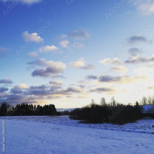 Winter sunset with snow on the ground and clouds in the sky