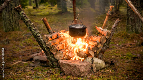 Foto Pot hanging over an intense fire in a bushcraft setting.