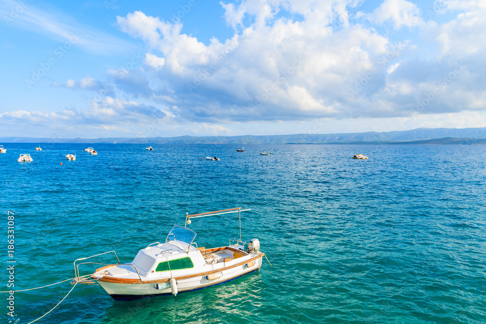 White fishing boat on blue sea and beautiful sunny sky with white clouds in Bol port, Brac island, Croatia