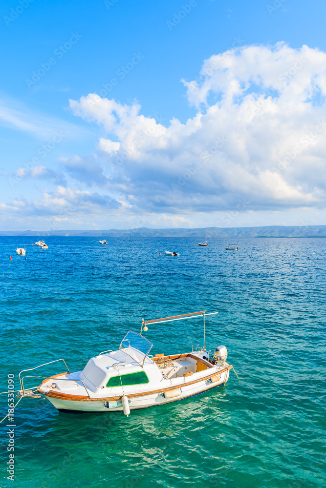 White fishing boat on blue sea and beautiful sunny sky with white clouds in Bol port, Brac island, Croatia