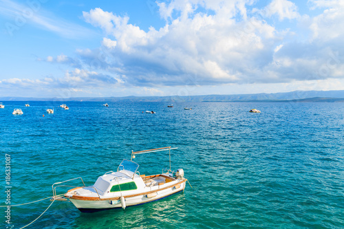 White fishing boat on blue sea and beautiful sunny sky with white clouds in Bol port, Brac island, Croatia