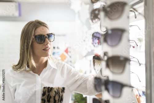 Beauty woman in optical store with sunglasses looking at display