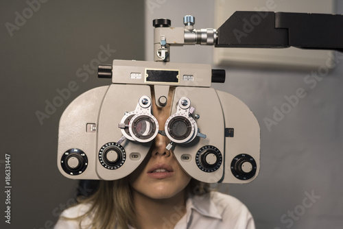 Woman ready for eye test with phoropter and calibrating glasses photo