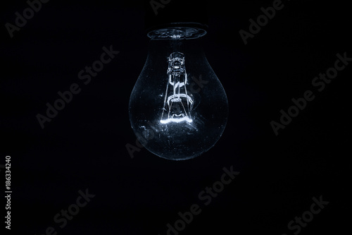Eine Glühlampe mit sichtbarem Glühstab in der Dunkelheit