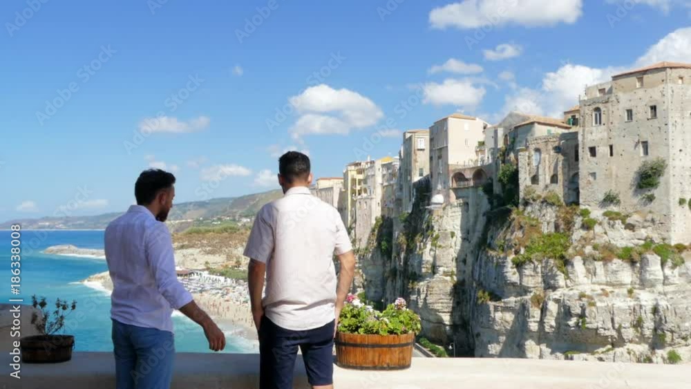 Two businessmen are breathed in a beautiful place at sea in Italy in Calabria in the city of Tropea, the boys share their impressions of travel and do selfie on the background of the sea Two businessmen are breathed in a beautiful place at sea in Italy in Calabria in the city of Tropea, the boys share their impressions of travel and do selfie on the background of the sea