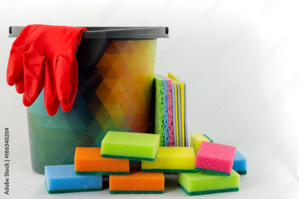 Cleaning concept kit - colored bucket, hand broom, rubber gloves and sponges on white background.